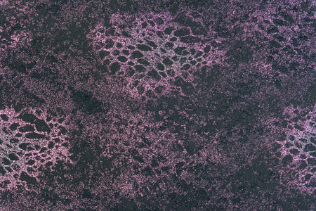 Abstract background, imitating reptile skin texture. An abundant, shimmering purple-pink coating (glitter) is applied over a dark base. Material for fashionable clothing, footwear, bags, furniture upholstery, curtains, or texture for design and packaging.の写真素材
