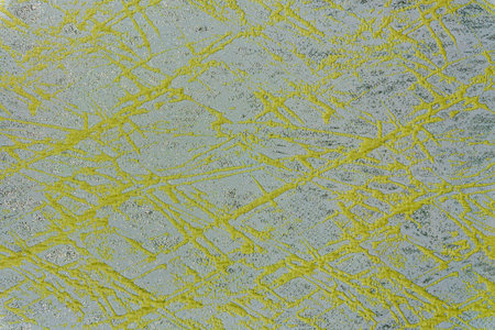 Textile texture with bright lime green abstract paint splatter over a shimmering silver background....