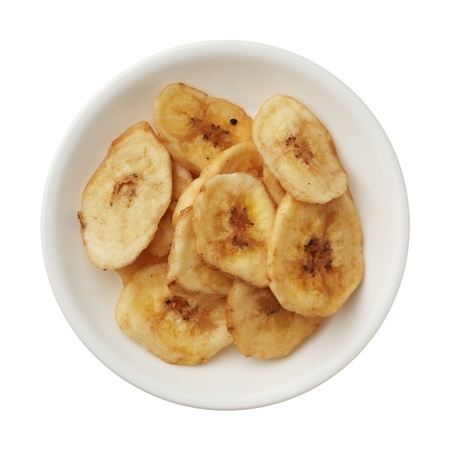 Dried banana chips in a bowl isolated on white backgroundの写真素材