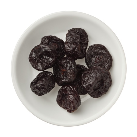 Isolated dried plums in a bowl over white backgroundの写真素材