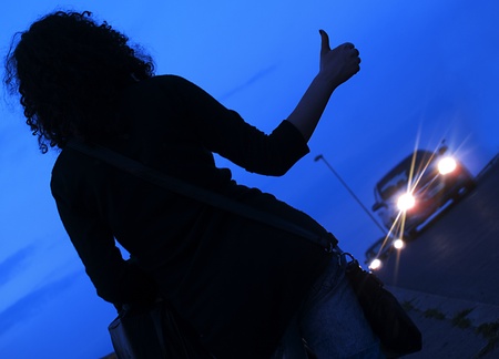  young woman  hitch hiking on a road in the nightの写真素材