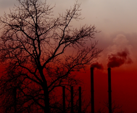Air pollution by smoke coming out of two factory chimneys on sunset の写真素材