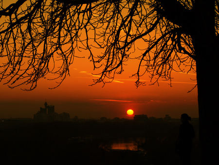 summer sunset with red sky on river, and many silhouttesの写真素材
