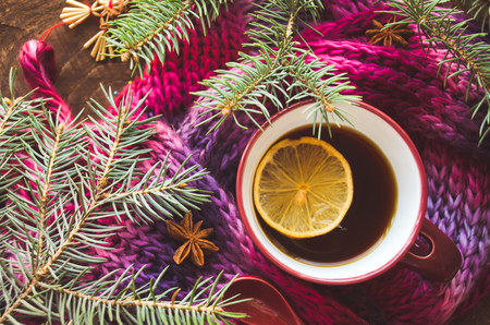 Cup of lemon tea covered with scarf. Christmas tree in background. Winter concept.の写真素材
