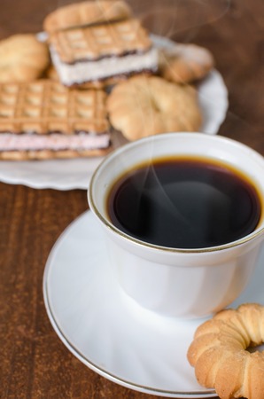 Cup of hot coffee with pastry. Dark wooden background. Selective focus.の写真素材