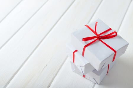 Christmas gift boxes with red ribbons on white wooden table. Christmas background.の写真素材