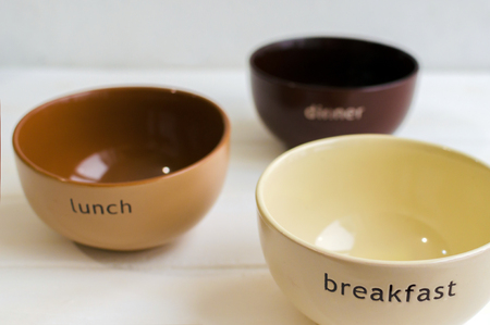 Set of bowls. Written breakfas, lunch, dinner on ceramic bowls.の写真素材