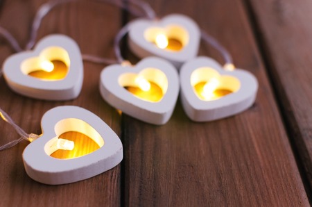 Love valentine's day with hearts garland lights on old wooden background. Top view.の写真素材