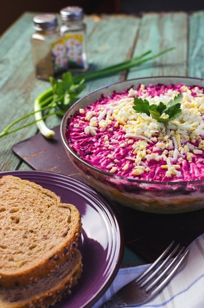 Traditional Russian herring under a fur coat in transparent plate with parsley. Rustic style. Selective focus.の写真素材