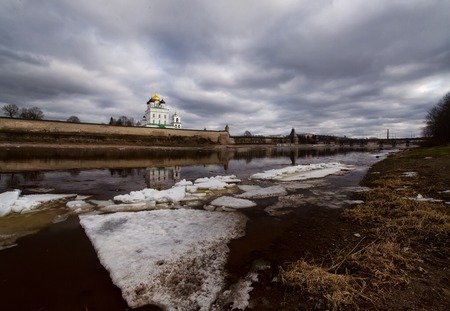 Ancient fortress on the river bank. Russia. Pskov Kremlin. Pskov spring time. ice drift. Beautiful landscape. Letters on river bank in russian language Russia starts hereの写真素材