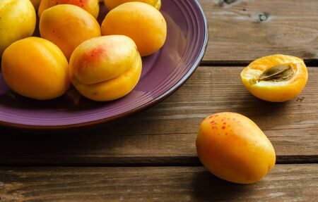 Delicious ripe apricots in a wooden bowl on the table close-up. Selective focus.の写真素材