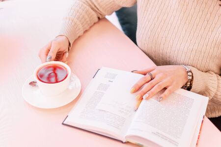Close up of beautiful young woman s hands holding fruit hot tea cup at cafe shop. Selective focus.の写真素材