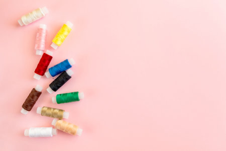 Sewing supplies and accessories for needlework Multicolored thread coils for sewing clothes on pink...