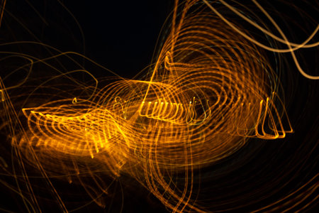 Gold light painting photography, long exposure photo of golden fairy lights in a loop against a...