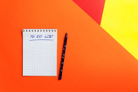 Top view of office tools with blank notebook on orange, yellow and red background Space for text....
