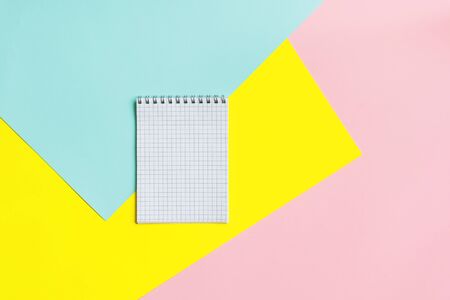 Top view of office tools with blank notebook on blue, yellow and pink background. Space for text. Top view.の写真素材