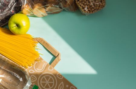 Food for quarantine isolation period flat lay on light blue background with copy space. Cooking oil, pasta, water and beans. Crisis food supplies. Delivery, donation concept. Space for text.の写真素材