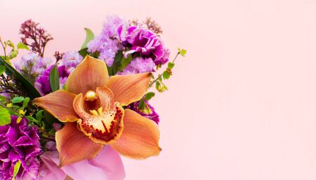 Bunch of beautiful flowers, orchid isolated on light pink background. Close-up. Florist shop or feast concept.の写真素材