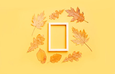 Colorful leaves frame on yellow background with copy space. Halloween or thanksgiving concept.