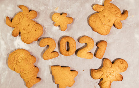 Woman hand cutting cookies, year 2021 on dark board with baking flour. rolling pin, flour and shape of new year figures.の写真素材
