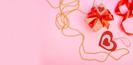 Valentines Day or birthday presents. Valentines Day gifts with a red paper heart, golden beads on a pink background. Top view.の写真素材