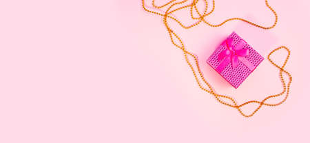 Valentines Day or birthday presents. Valentines Day gifts with a pink ribbon and golden beads on a pink background. Top view. Pink background. Handicraft gifts.の写真素材