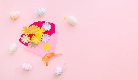 Eggs and craft flowers on pink backround on Easter day. Celebrating Easter at spring.