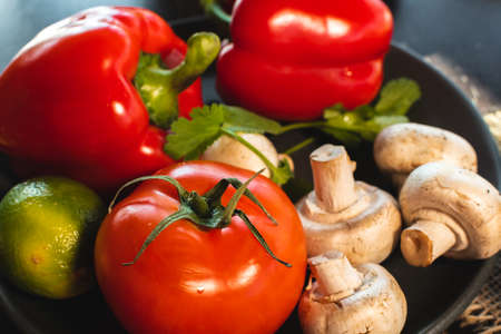 Variety of vegetables. Bell pepper, tomato and champignon on dark plate.の写真素材