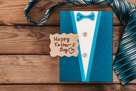 Happy Fathers Day gift blue box with tie on a rustic wood background.