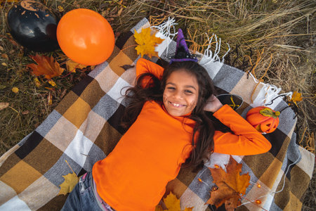Halloween kids. Portrait smiling girl with brown hair laying on blanket . Funny kids in carnival...