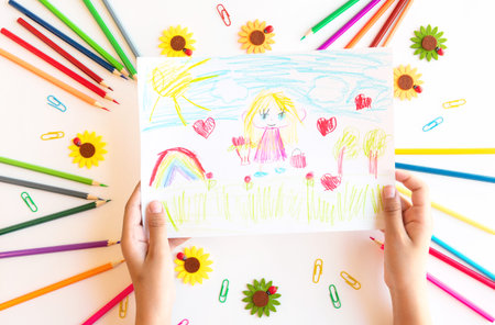 A child draws a postcard for mothers day. Beautiful landscape with mom drawn with pencils.