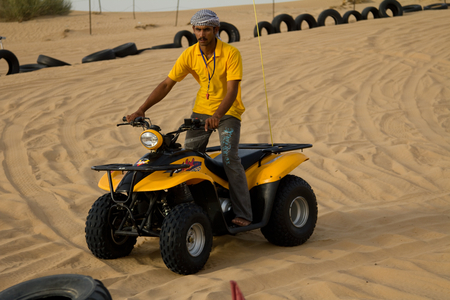 DUBAI, UAE - APRIL 20, 2012: Safari camp staff riding an ATV (All Terrain Vehicle). ATV rides are offered to tourists as part of the camp experience.のeditorial素材