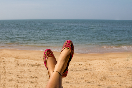 A lady wearing a pair of traditional Indian women's shoes (jutis) at the Anjuna beach in Goa, Indiaの写真素材