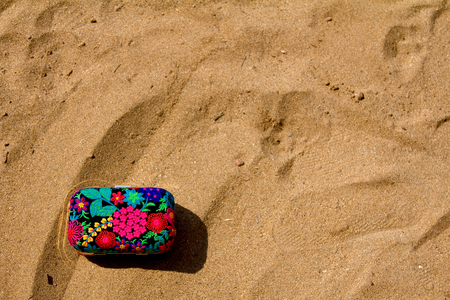 Traditional ethnic Indian clutch (women's handbag) on sand at a beach in Goa, Indiaの写真素材