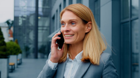 Happy enthusiastic excited woman talking on mobile phone outdoors sharing good experience with friend remotely chatting on smartphone joyful businesswoman speaks on telephone communicating with clientの写真素材