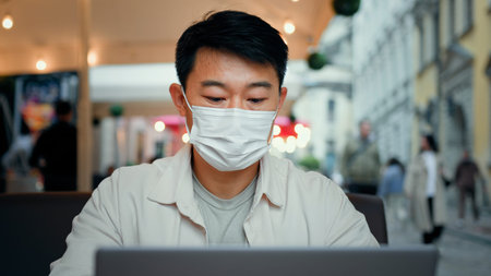Smiling man in protective mask look at laptop screen chatting remote with friend on social media...