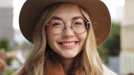 Close-up smiling Caucasian 20s woman smile broadly with white teeth looking at camera happy girl...