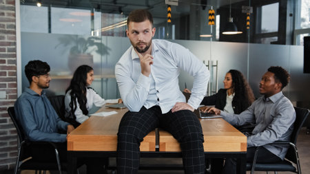 Thoughtful thinking pensive man leader boss businessman think about startup idea company CEO sitting on office table on background of multiracial business team workers group discuss project teamworkの写真素材