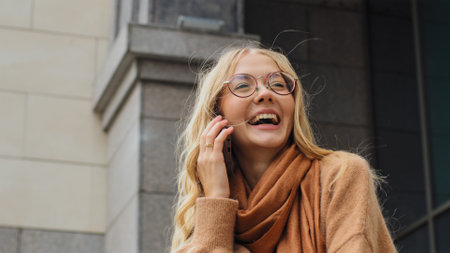 Happy emotional Caucasian smiling laughing girl talking mobile phone cheerful woman smile laugh friendly talk smartphone call cellphone conversation outdoors in city female lady listening good newsの写真素材