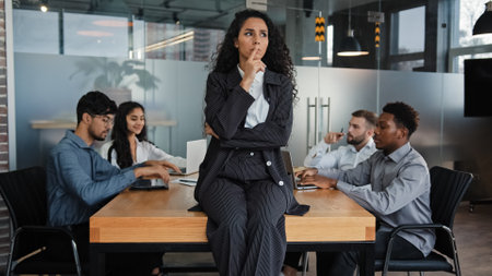 Pensive thinking female company CEO thoughtful businesswoman sitting on table office desk in boardroom think multicultural employees multiethnic workers colleagues work meeting brainstorm backgroundの写真素材