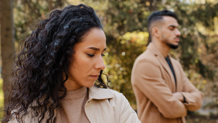 Close up offended upset curly girl in background angry guy family quarrel woman turns away from man hispanic couple stand ignoring each other outdoors conflict misunderstanding unhappy female feel sadの写真素材