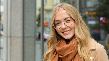 Close up female outdoors smiling laughing Caucasian woman smile looking at camera girl blonde model with healthy white teeth happy lady with glasses posing on street in city attractive student outsideの写真素材