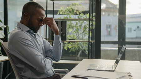 Overworked African American mature business man working laptop in office suffer with eye strain exhausted sick fatigued middle-aged businessman feel pain discomfort eyesight headache health migraineの写真素材