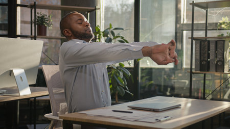 Relaxed African American mature businessman senior happy man finish computer work close laptop relaxing in sunny warm comfortable office male specialist stretch muscles put hands behind head day endの写真素材