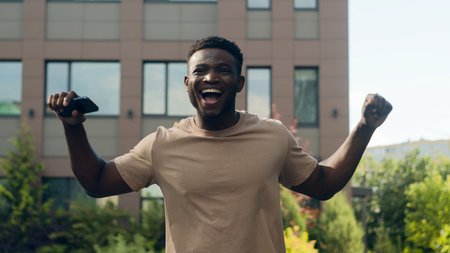 African American happy success winner man ethnic guy in city male outdoors win victory achieve with...