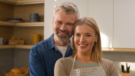Happy family portrait at home cooking kitchen adult Caucasian couple lovely husband and wife man and woman spouses homeowners cuddling look at each other smiling to camera insurance mortgage loanの写真素材