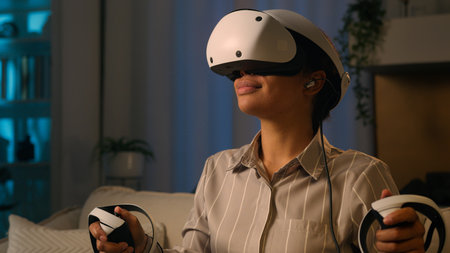 African American woman in VR helmet virtual reality glasses play modern metaverse video game simulation female gamer playing with 3D goggles at night cyberspace world explore futuristic space at homeの写真素材