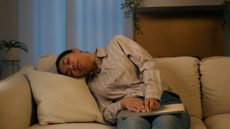 Tired exhausted African American businesswoman night working laptop from home overworked woman fall asleep on couch sick weary sleeping female flopped down on sofa chronic fatigue lack energy relaxingの写真素材
