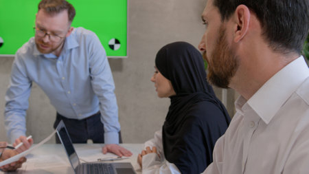 Multiethnic colleagues businessmen and muslim businesswoman in hijab teamwork in office boardroom business team talk brainstorming discussion with green screen interactive board copy space chroma keyの写真素材