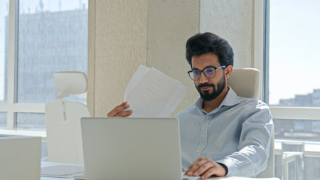 Arabian Indian man tired businessman suffer high temperature uncomfortable heat summer blowing waving papers make wind sit in hot office think project on laptop solve problem broken air conditionerの写真素材